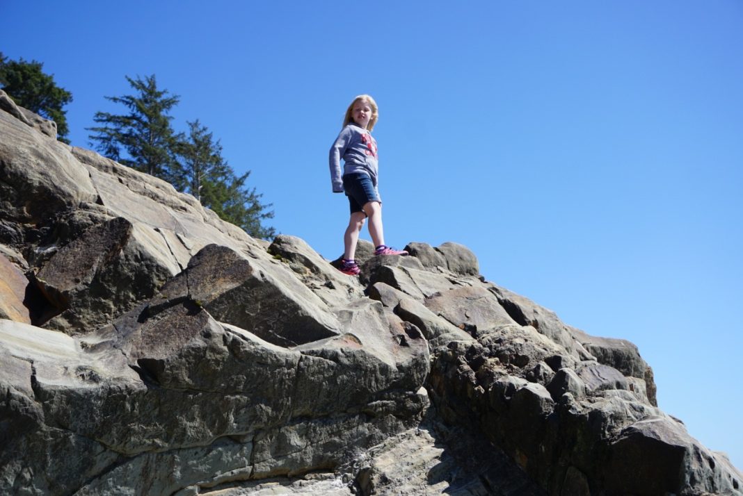 a kid standing on a huge rock