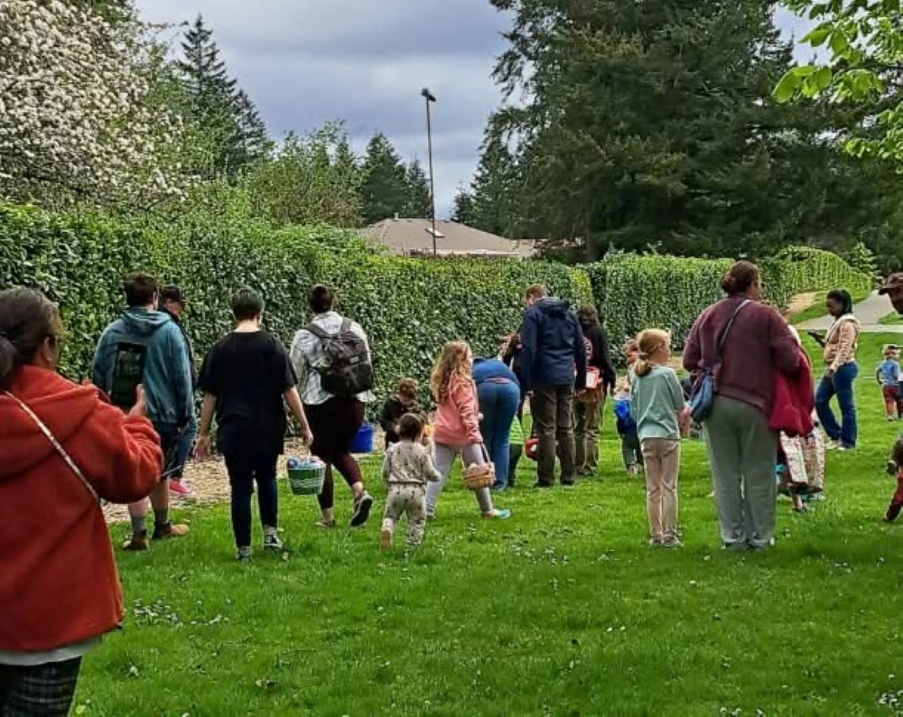 a bunch of kids with Easter baskets and adults walk through a grassy area