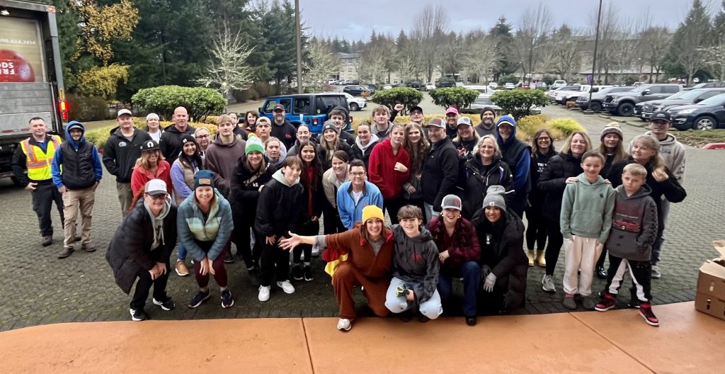 a large group of people of all ages post for a photo in a parking lot