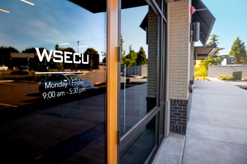 angled photo of the side of the WSECU Hawk's Prairie building with large glass windows, and words on the door: "WSECU"