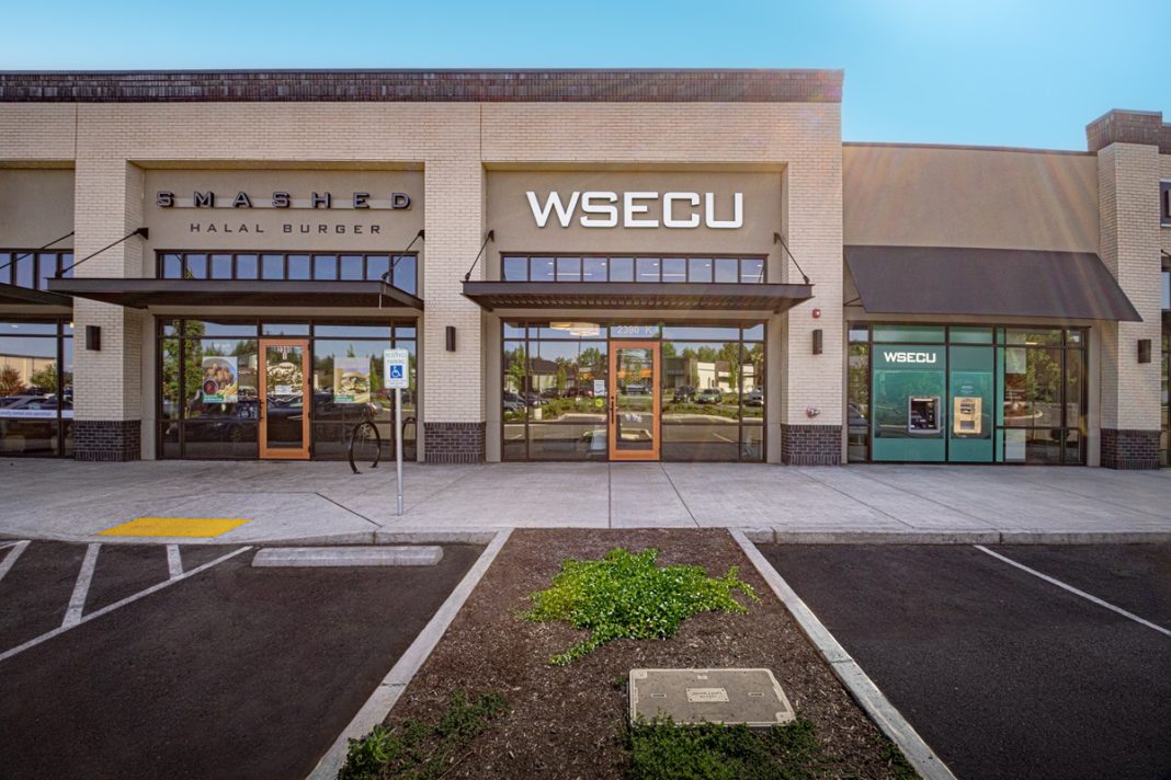 outside of the WSECU Hawks Prairie branch with the letters "WSECU" in white on the front and empty parking spaces in front.