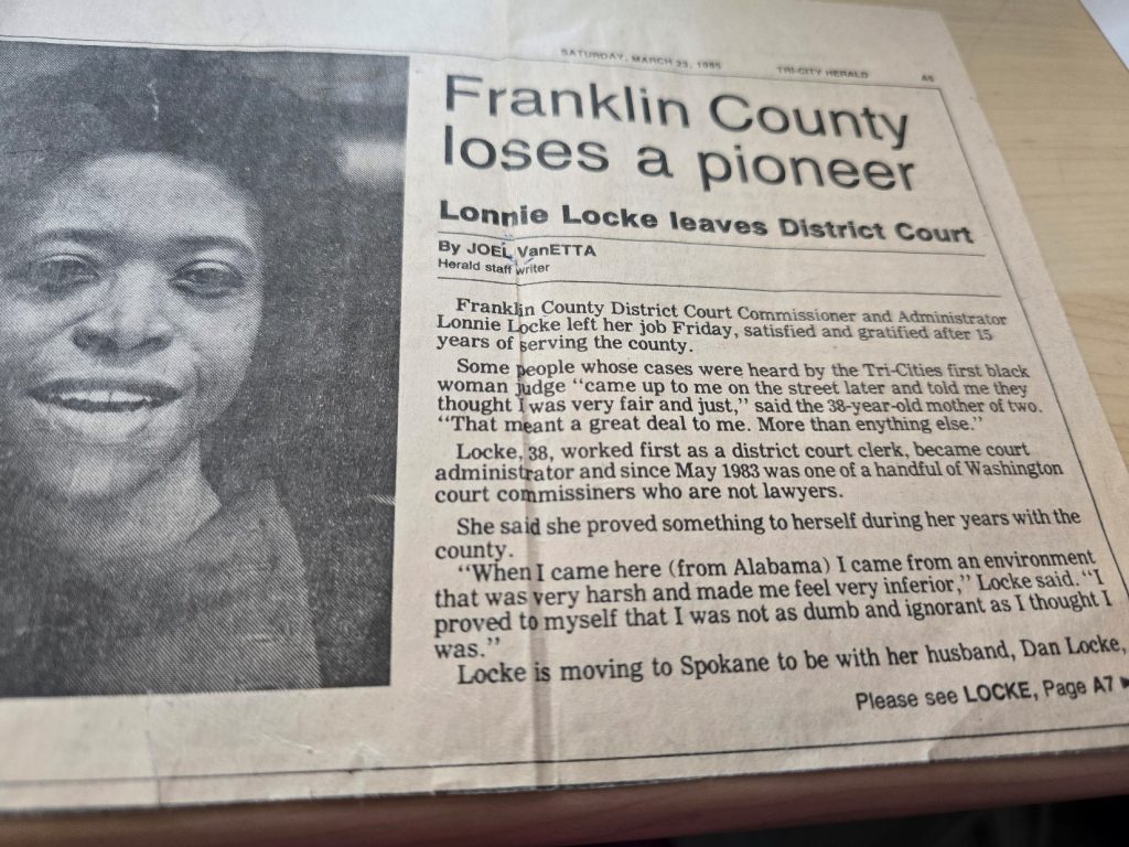 Newspaper clipping that says." Franklin County loses a pioneer. Lonnie Locke leaves district court. By Joel VanETTA. Harold staff writer. Franklin County, District Court, commissioner and administrator, Lonnie Locke left her job Friday, satisfied and gratified after 15 years of serving the county. Some people whose cases were heard by the Tri-Cities first black woman judge “Came up to me on the street later and told me they thought I was very fair and just,” said the 38-year-old mother of two “That meant a great deal to me. More than anything else.” Locke, 38, worked first as a district court clerk, became court administrator and since May 1983 was one of a handful of Washington court commissioners who are not lawyers. She said she proved something to herself during her years with the county. “When I came here (from Alabama) I came from an environment that was very harsh and made me feel very inferior,” Locke said. “I proved to myself that I was not as dumb and ignorant as I thought I was.” Locke is moving to Spokane to be with her husband, Dan Locke, please see lock page A7