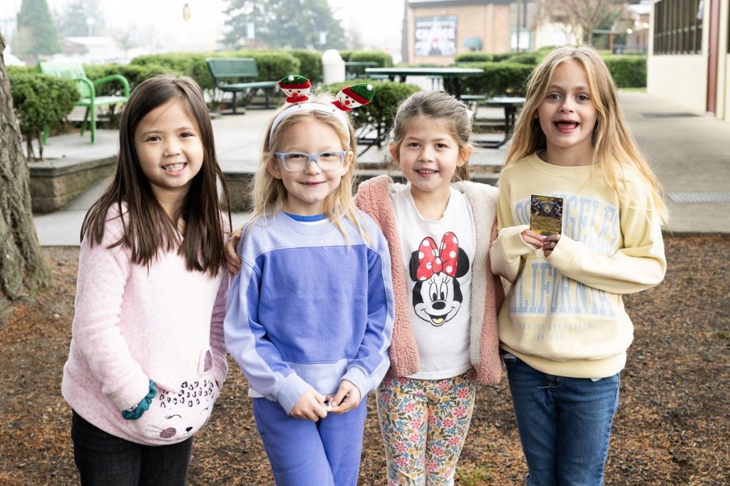 four young girls stand in a row, smiling for the camera