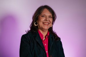 Martha Correa, headshot against a purple and white background