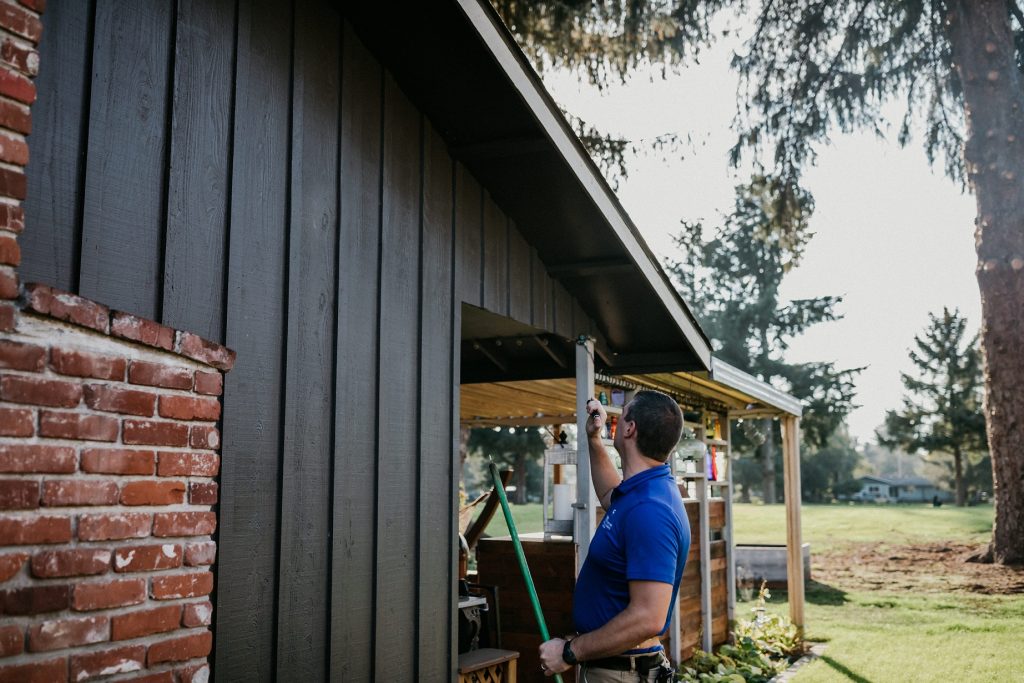 a Boggs home inspection technician looks at a houses eve's with a flashlight