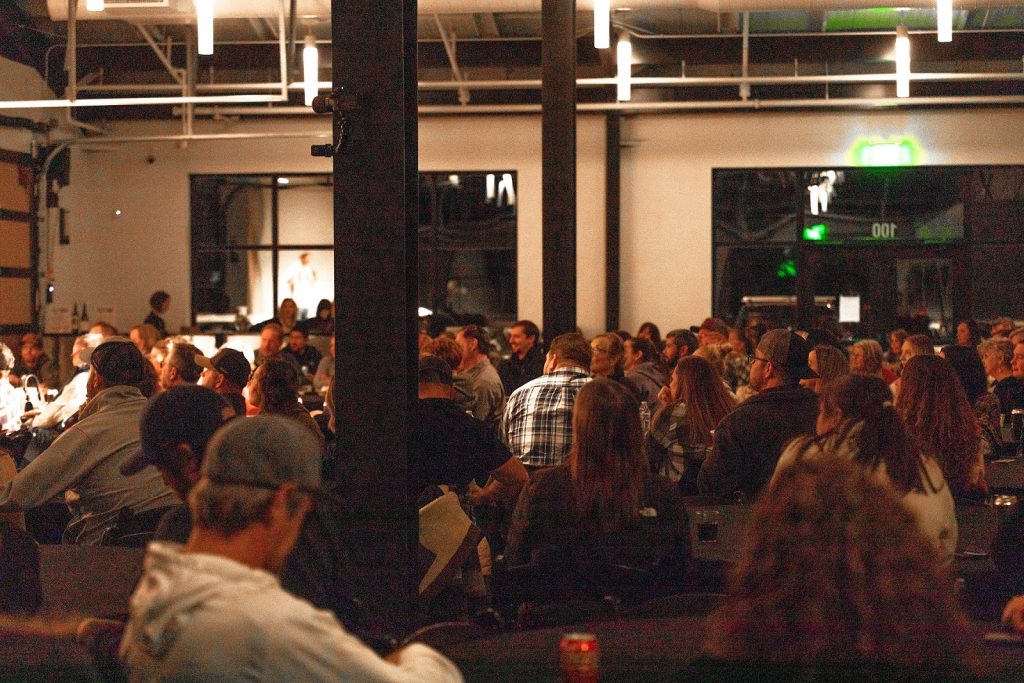 a large group of people sit at large tables in the Stone City Event Center 