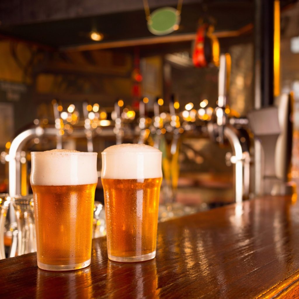 Two light-colored beers sitting on the wooden bar at Charlie's Bar in Olympia