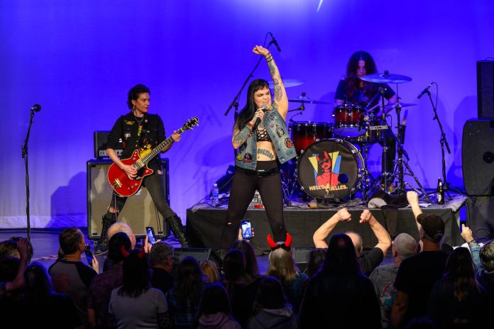 Hell's Belle rock group performing on stage to a crowd of people