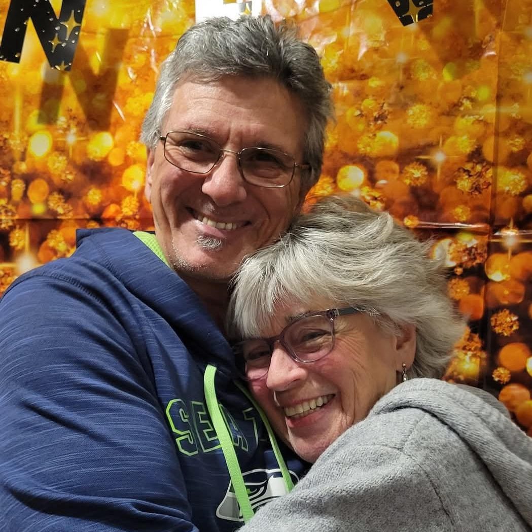 Thane and Peggy Bryenton smile at the camera while hugging each other