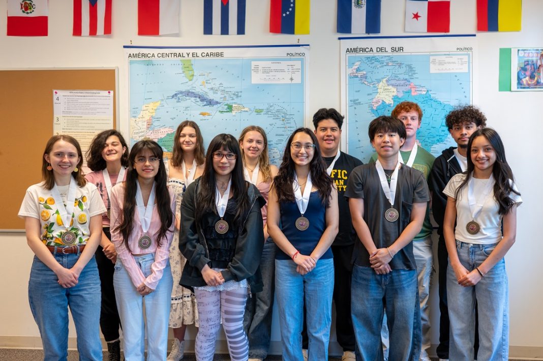 a group of high school students smile for a photo standing side by side, each with a medal around their neck