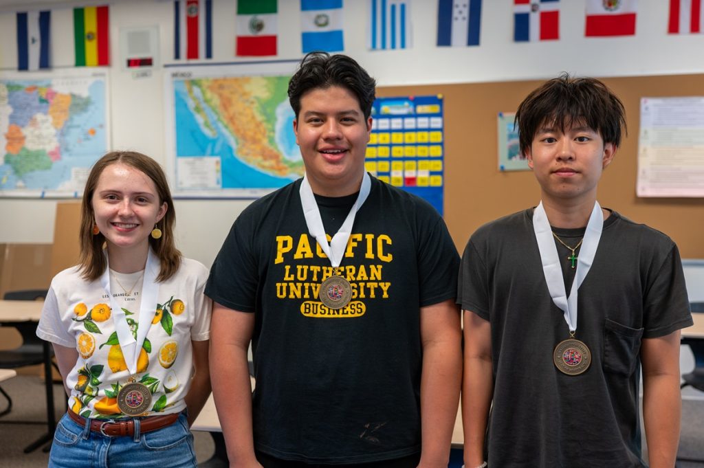 3 high school students smile for a photo standing side by side, each with a medal around their neck