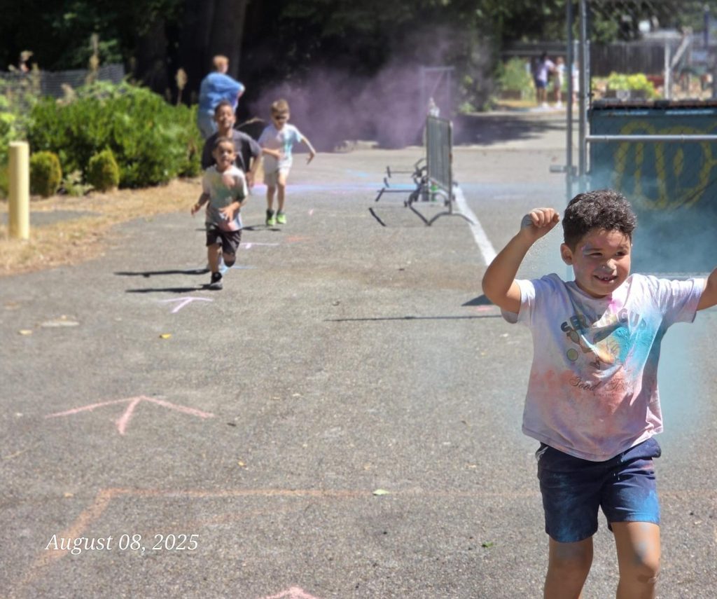 Kids running on a concrete play area with a mister