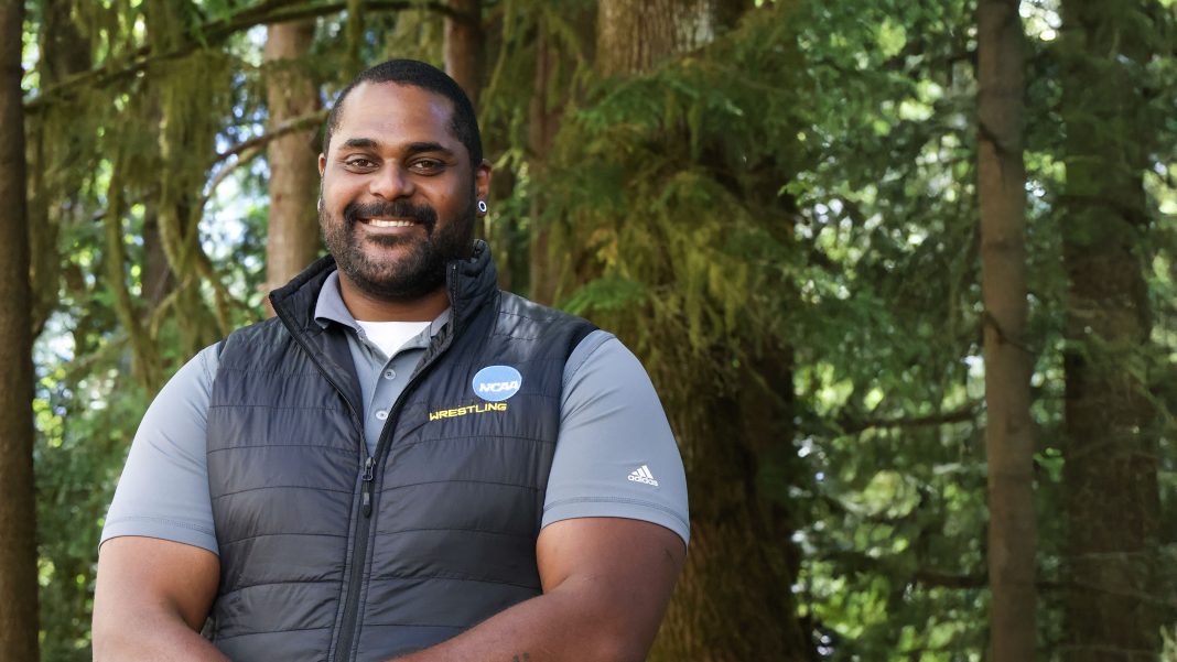 Emanuel Scott posing for a photo in front of tall evergreen trees