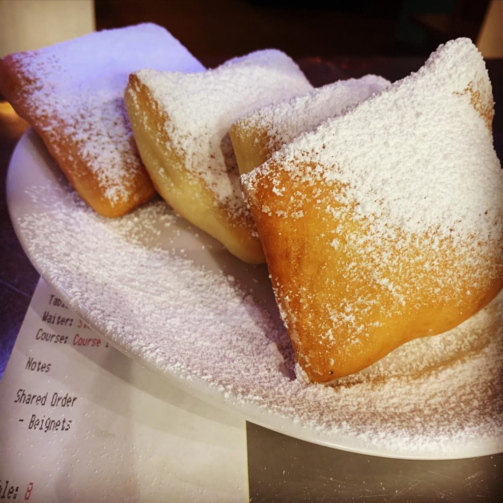 4 powered sugar coated beignets on a plate
