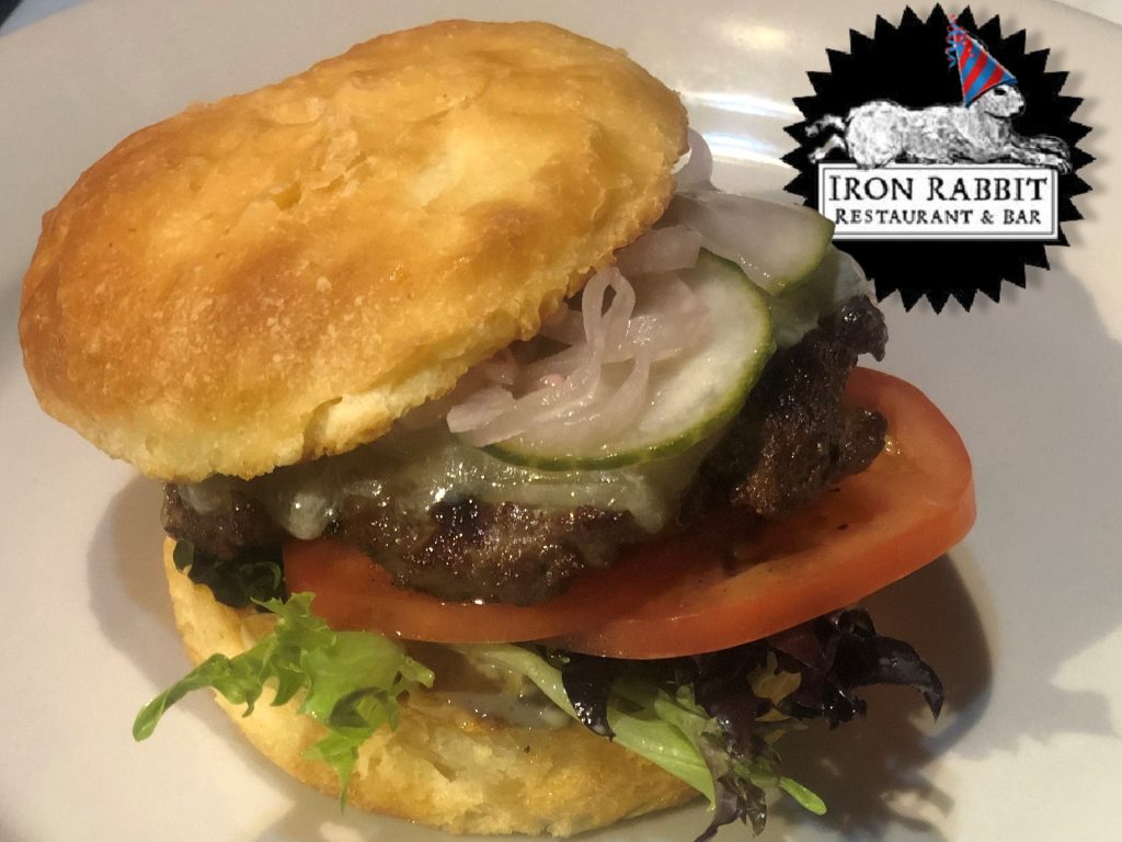 a burger with lettuce, tomatoes, cheese and mushrooms on a plate