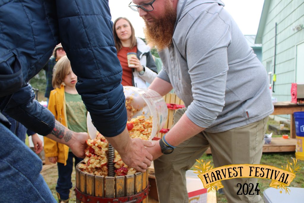 Two men poor apples into a cider press