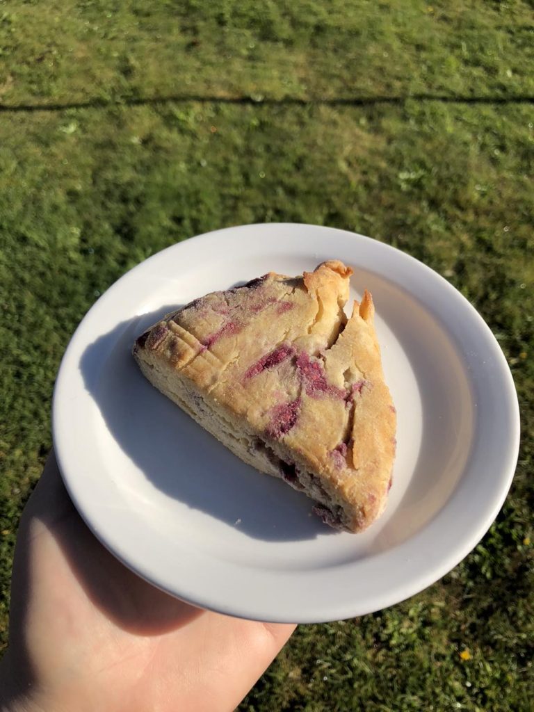 a scone on a plate being held by a hand