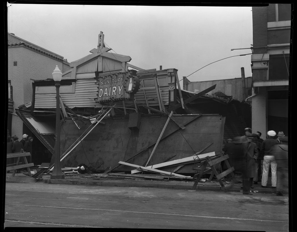 black-and-white photo of Sanitary Dairy building with sign still visible after bombing - roof and walls collapsed