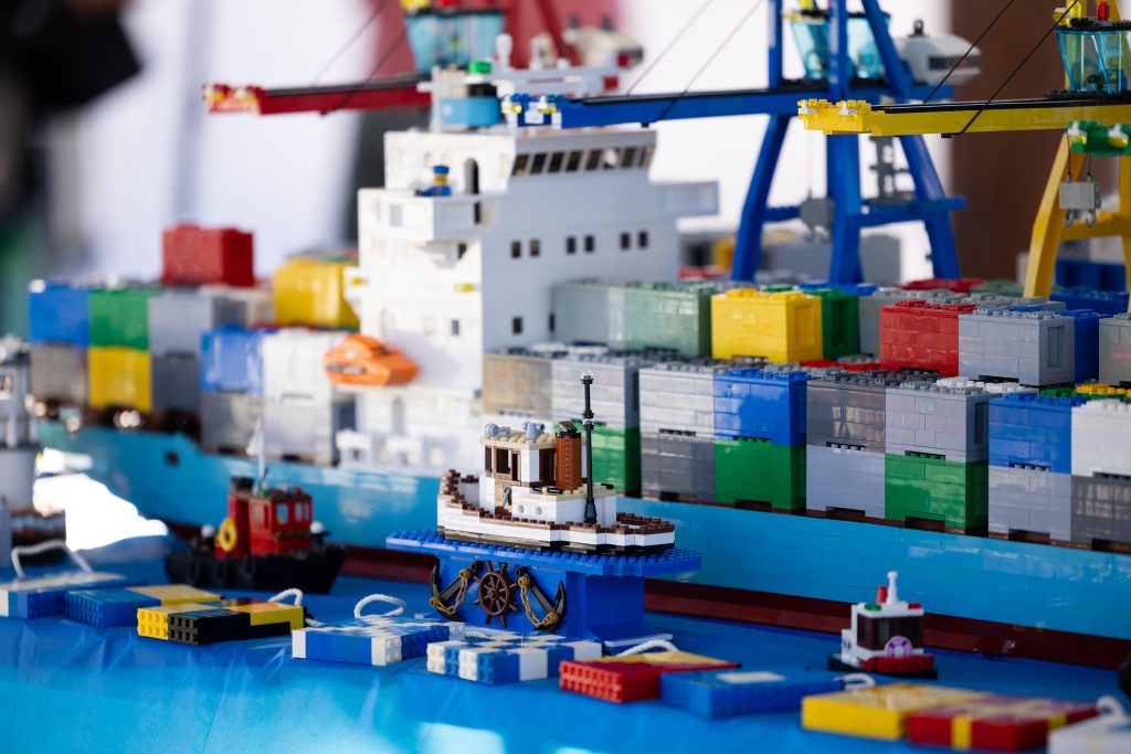a LEGO ship with smaller ships next to it on a blue matt